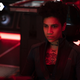A woman with short hair and a chest tattoo sits on the bridge of a spaceship in The Expanse.